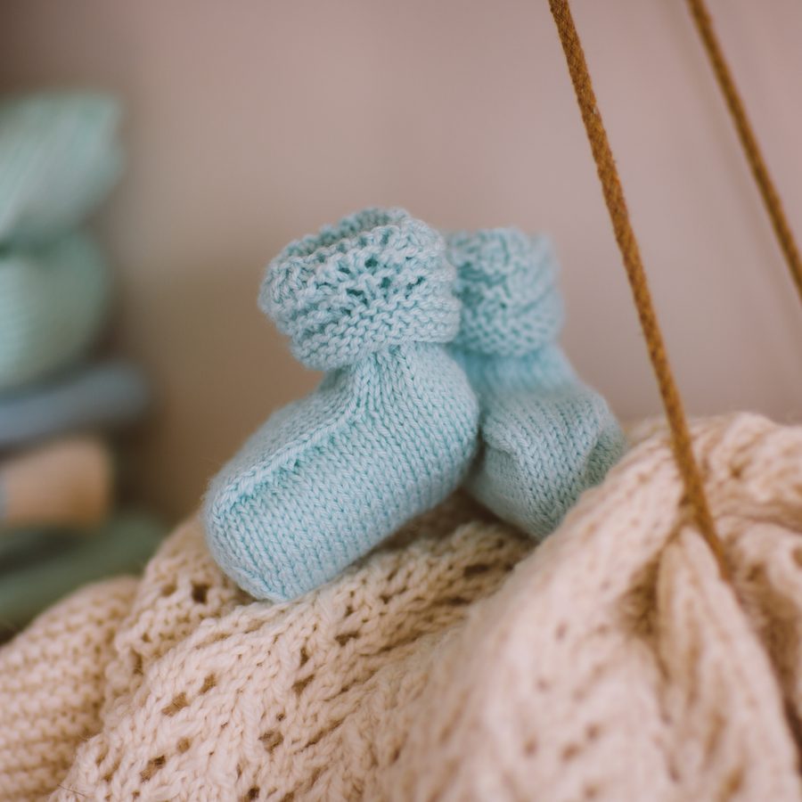 Hand-knitted baby booties resting on a knitted blanket